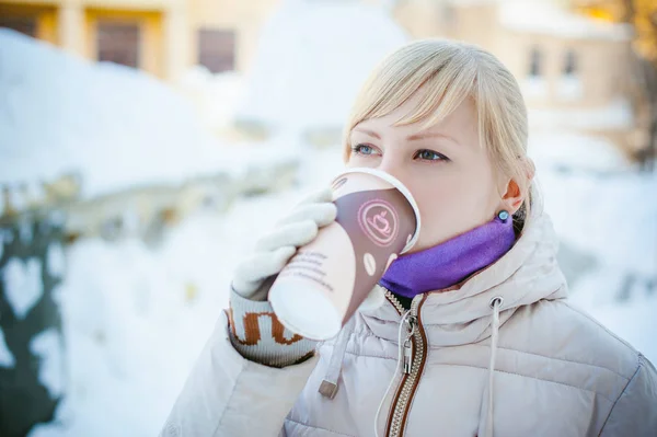 Wanita muda berpakaian hangat minum kopi takeaway dari cangkir di jalan di musim dingin — Stok Foto