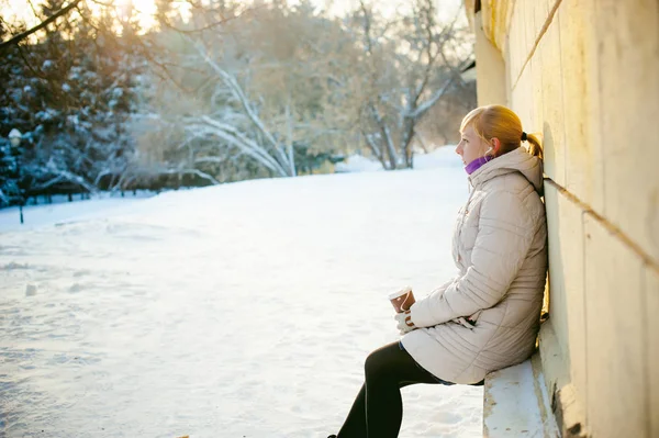 Mladá žena na sobě teplé oblečení s sebou kafe z šálku na ulici v zimě — Stock fotografie