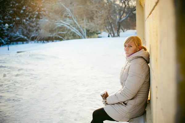 Jonge vrouw gekleed in warme kleren afhaalmaaltijden koffie drinken uit de beker op straat in de winter — Stockfoto