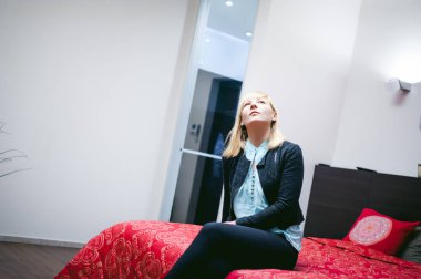 oturan sarışın kadın evde oturma odasında kanepede oturan.