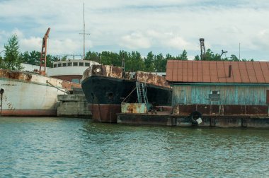 İskele nehirde paslı gemilerle