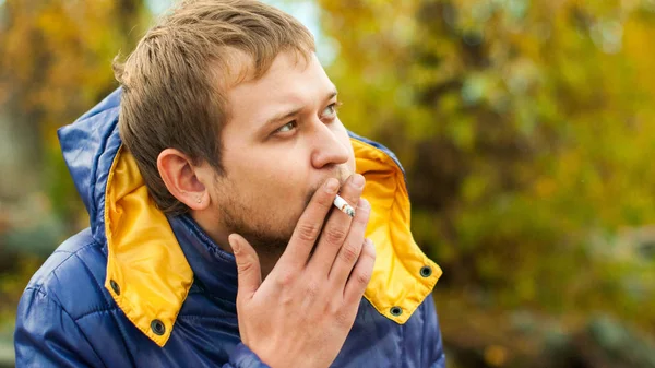 Retrato de um homem fumando em uma rua na jaqueta de outono — Fotografia de Stock