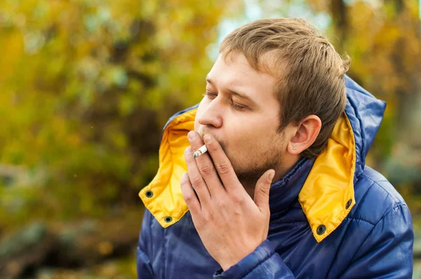 Portrét muže kouření na ulici v podzimní bunda — Stock fotografie