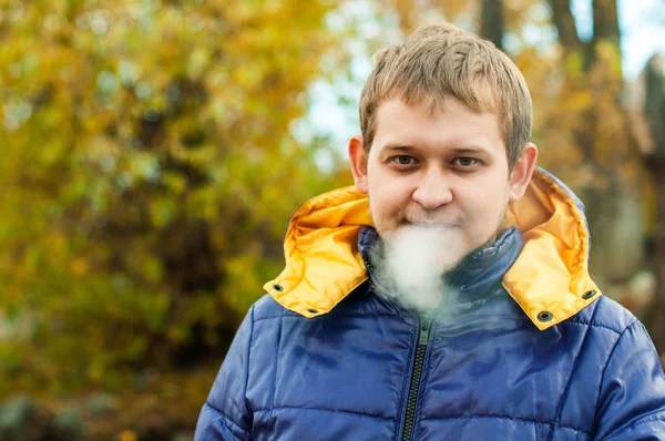 Retrato de un hombre fumando en una calle con chaqueta de otoño — Foto de Stock