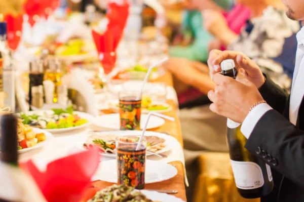Fundo Desfocado Homem Abre Vinho Espumante Mesa Festiva Decorada Tons — Fotografia de Stock