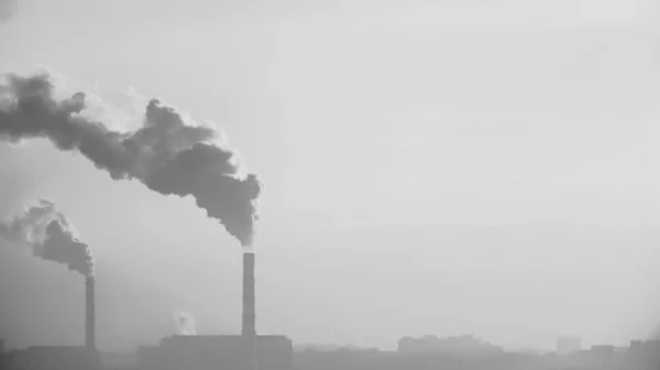 Fumaça da chaminé de uma empresa industrial em um fundo de cidade turva — Fotografia de Stock