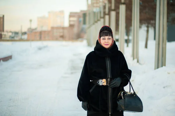 Portrait of an adult woman in warm clothing, a traditional headscarf, in the urban environment in the winter — Stock Photo, Image