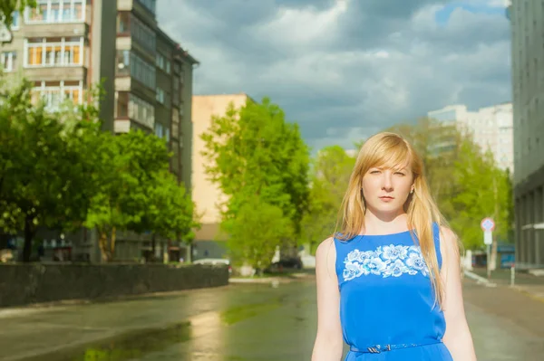 Vrouw Blond in een blauwe jurk wandelen langs stad straat tegen een achtergrond van stedelijke architectuur en zomer Siberische schoonheden — Stockfoto