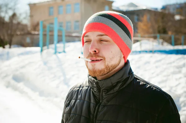 Retrato de un hombre con barba con bigote, fumando un cigarrillo, con una cara emocional al aire libre — Foto de Stock