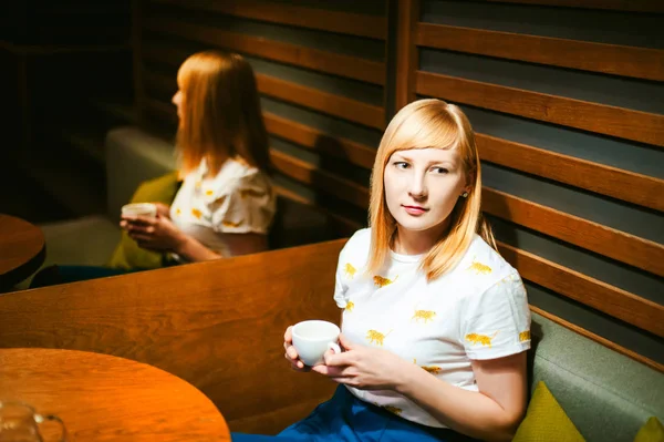 Mujer rubia joven con camiseta blanca con estampado, hora del almuerzo en la cafetería visitada — Foto de Stock