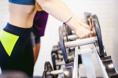 Parlak beyaz bir spor salonundaki kız. Spor malzemelerinin yanında iki genç atletik kadın, halterleriyle halterlerini kaldırarak nakil için hazırlanıyorlar. Sağlıklı yaşam tarzı, iyi ruhlar.