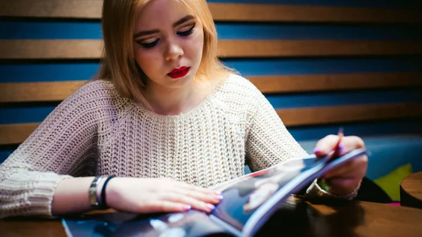 Dergi okuma sırasında kafede oturan genç bayan resmi. — Stok fotoğraf