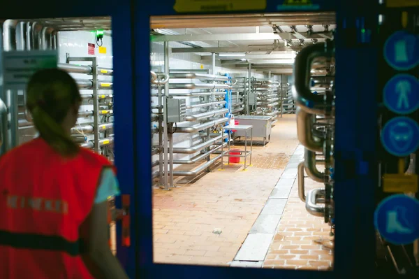 Női munkavállalók sör gyári. álló nő köntöst, állandó háttér sorban élelmiszer-termelés, ellenőrzés irányítása berendezések gyártására — Stock Fotó