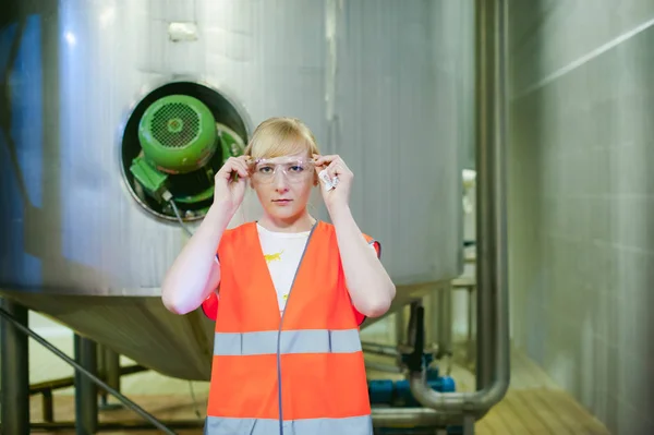 Female worker on beer factory. portrait woman in robe, standing on background line Food production, Inspection management control Equipment for production — Stock Photo, Image