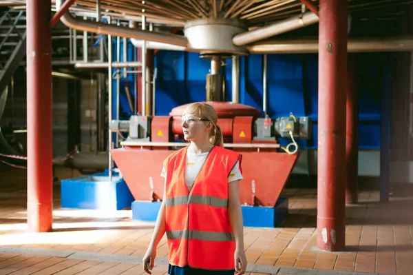 Female worker on beer factory. portrait woman in robe, standing on background line Food production, Inspection management control Equipment for production