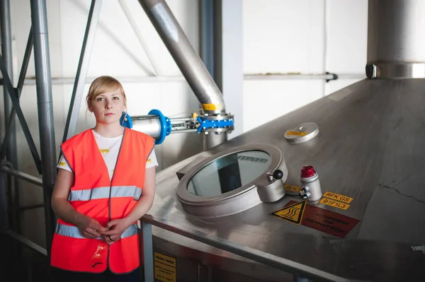 Female worker on beer factory. portrait woman in robe, standing on background line Food production, Inspection management control Equipment for production