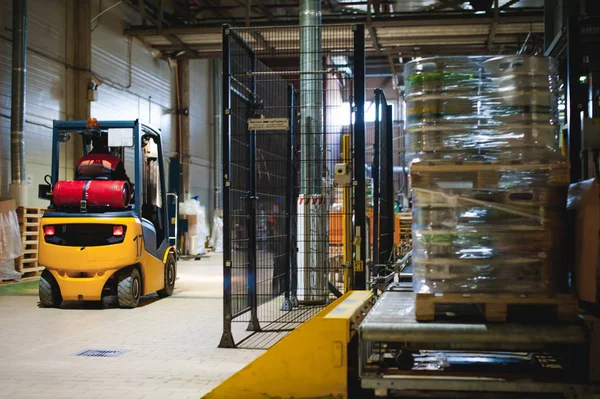 Warehouse employee in Overalls clothes, driver Reachtruck busy working on logistics Moving on loader pallets with beer kegs on line of factory for production of beer. human labor in manufacturing