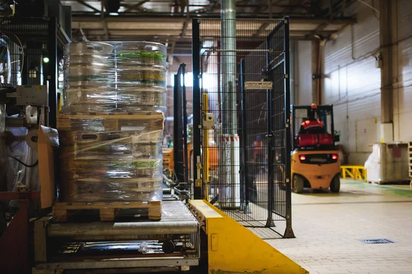 Warehouse employee in Overalls clothes, driver Reachtruck busy working on logistics Moving on loader pallets with beer kegs on line of factory for production of beer. human labor in manufacturing — Stock Photo, Image