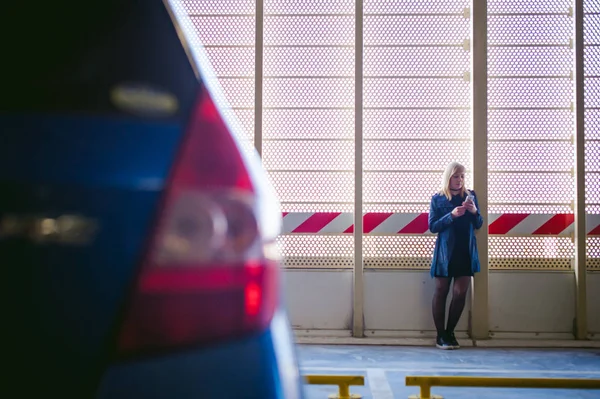 Mujer en el estacionamiento en el fondo azul del coche — Foto de Stock