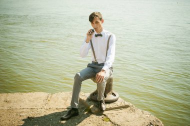 şık şık gri pantolon askısı ve papyon ile beyaz gömleği giyince giyinmiş genç sıska adam,