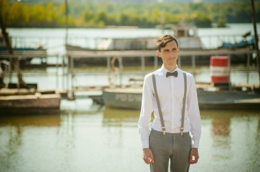 şık şık gri pantolon askısı ve papyon ile beyaz gömleği giyince giyinmiş genç sıska adam,