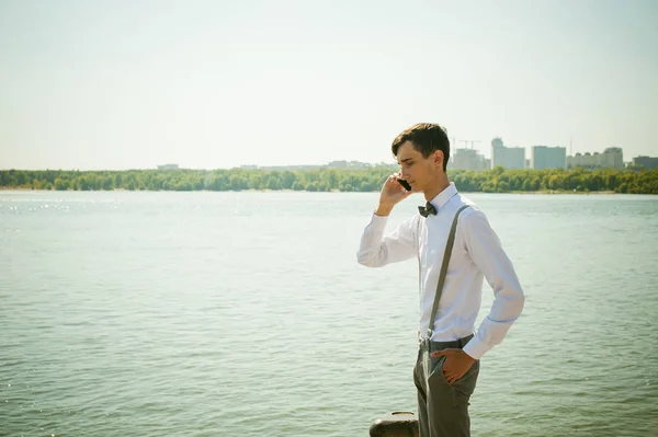 Joven flaco, elegantemente vestido con estilo en camisa blanca, pantalones grises con tirantes y pajarita — Foto de Stock