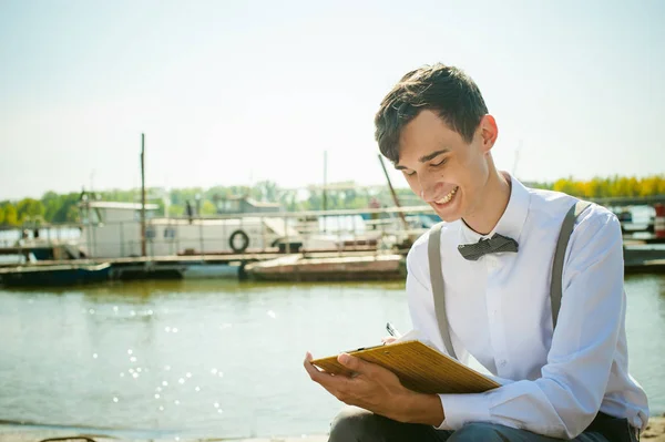 young skinny man, elegantly stylishly dressed in white shirt, gray trousers with suspenders and bow tie