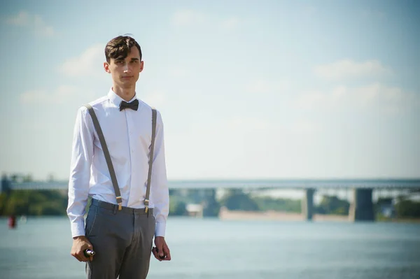 Joven flaco, elegantemente vestido con estilo en camisa blanca, pantalones con tirantes y pajarita — Foto de Stock