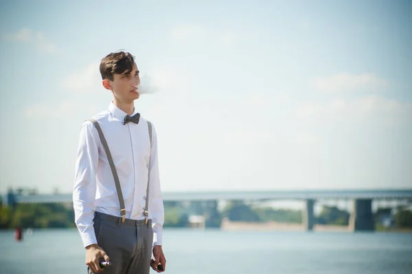 Giovane uomo magro, elegantemente vestito con camicia bianca, pantaloni con bretelle e papillon — Foto Stock