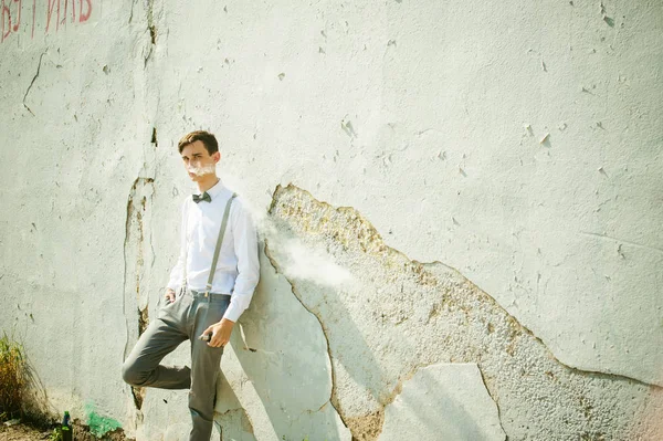 Joven flaco, elegantemente vestido con estilo en camisa blanca, pantalones grises con tirantes y pajarita — Foto de Stock