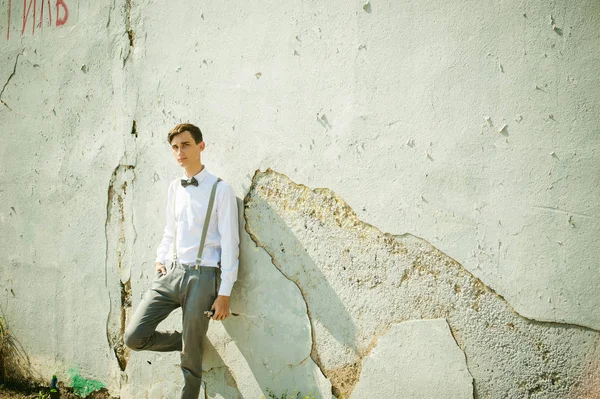 Joven flaco, elegantemente vestido con estilo en camisa blanca, pantalones grises con tirantes y pajarita — Foto de Stock