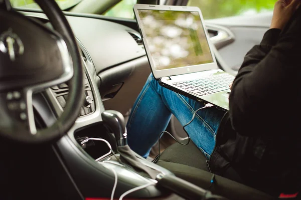 Человек с ноутбуком в машине тюнингует систему управления, обновляет программное обеспечение — стоковое фото
