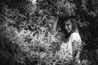 Siyah ve beyaz bir şapka çalıların arasında olan bir genç kadın portresi