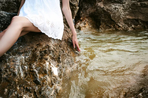 Retrato de una joven esbelta sobre piedras cerca del mar — Foto de Stock