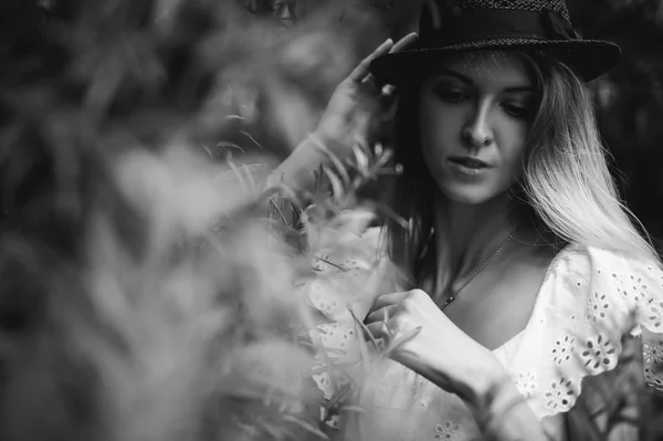 Retrato en blanco y negro de una joven con sombrero en arbustos —  Fotos de Stock