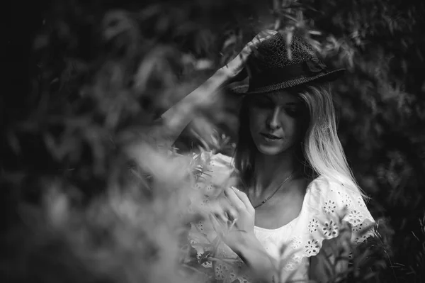 Retrato en blanco y negro de una joven con sombrero en arbustos —  Fotos de Stock