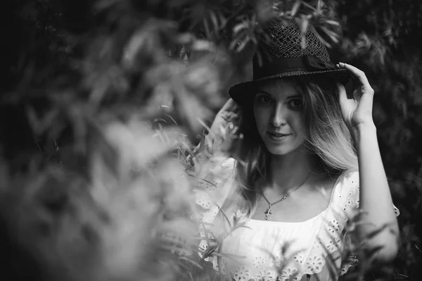 Ritratto in bianco e nero di una giovane donna con cappello tra i cespugli — Foto Stock