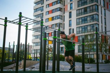 Güneşli sabah açık havada spor tesislerinde CrossFit egzersiz yapan yakışıklı seksi erkek vücut geliştirmeci atlet erkek. 