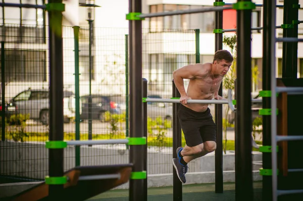 帅气性感的男性健美运动员人，做着在阳光明媚的早晨户外运动设施的运动量来找到锻炼。健康的生活方式的概念. — 图库照片