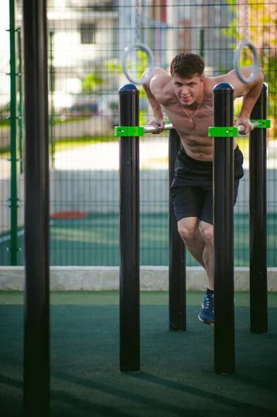 Güneşli sabah açık havada spor tesislerinde CrossFit egzersiz yapan yakışıklı seksi erkek vücut geliştirmeci atlet erkek. 