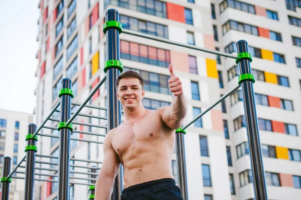 Guapo sexy hombre culturista atleta hombre haciendo entrenamiento crossfit en instalaciones deportivas en la mañana soleada al aire libre. Concepto de estilo de vida saludable. Preparación física del cuerpo. Modelo posa mostrando músculos —  Fotos de Stock