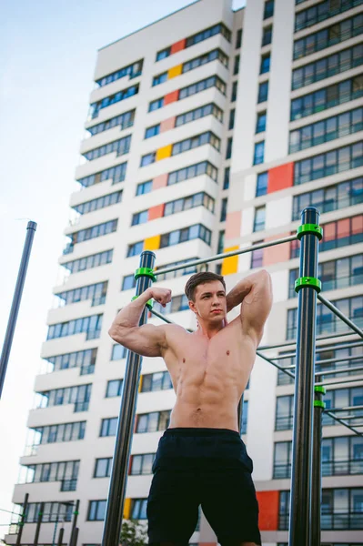 Güneşli sabah açık havada spor tesislerinde CrossFit egzersiz yapan yakışıklı seksi erkek vücut geliştirmeci atlet erkek. Sağlıklı yaşam konsepti. Vücudun fiziksel hazırlık. Kas gösterilen modeli pozlar