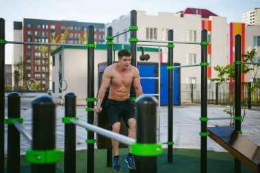 Güneşli sabah açık havada spor tesislerinde CrossFit egzersiz yapan yakışıklı seksi erkek vücut geliştirmeci atlet erkek. 