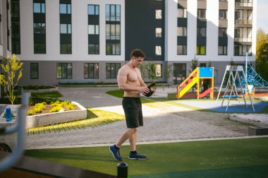 Yakışıklı seksi erkek vücut geliştirmeci atlet avluda dışında çıplak gövde ayakta olan adam. Sağlıklı yaşam konsepti.