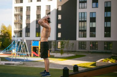 Yakışıklı seksi erkek vücut geliştirmeci atlet avluda dışında çıplak gövde ayakta olan adam. Sağlıklı yaşam konsepti.