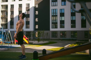 Yakışıklı seksi erkek vücut geliştirmeci atlet avluda dışında çıplak gövde ayakta olan adam. Sağlıklı yaşam konsepti.