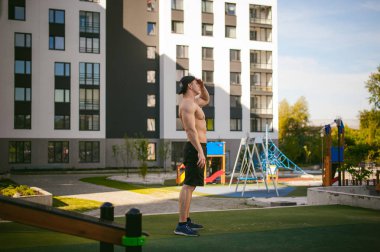 Yakışıklı seksi erkek vücut geliştirmeci atlet avluda dışında çıplak gövde ayakta olan adam. Sağlıklı yaşam konsepti.