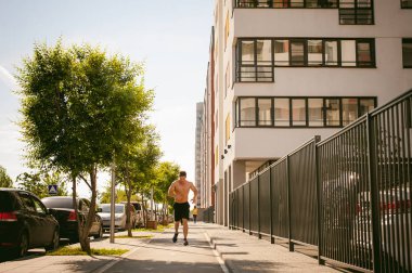 Yakışıklı seksi erkek vücut geliştirmeci sporcu adam çıplak gövde, kentsel avlularında bulunan açık hava çalıştırmak sabah ile