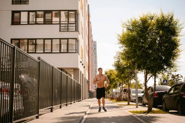 Yakışıklı seksi erkek vücut geliştirmeci sporcu adam çıplak gövde, kentsel avlularında bulunan açık hava çalıştırmak sabah ile