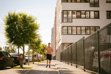 Yakışıklı seksi erkek vücut geliştirmeci sporcu adam çıplak gövde, kentsel avlularında bulunan açık hava çalıştırmak sabah ile